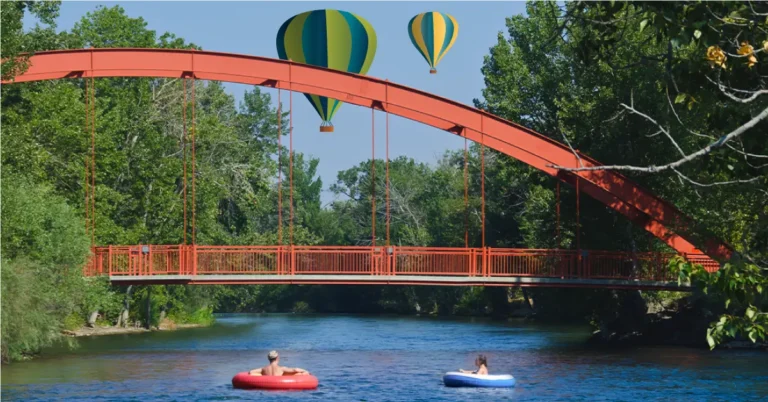 Image of a red bridge over a river with illustrated hot air balloons in the background.