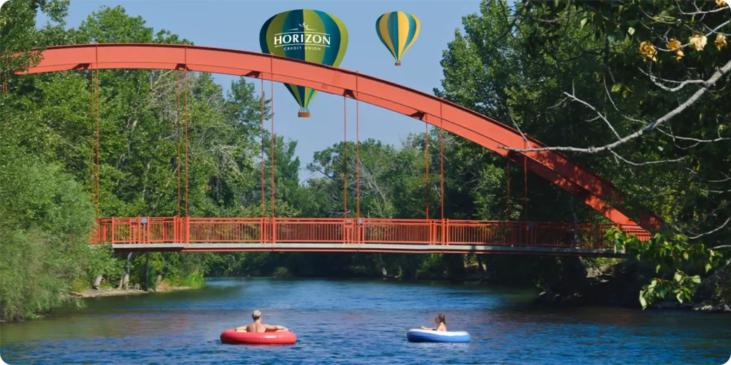 Image of a red bridge over a river with illustrated hot air balloons in the background.